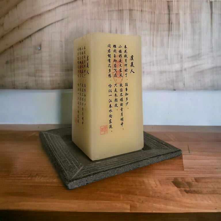Eine Kerze mit chinesischer Schrift sitzt auf einem Holztablett.