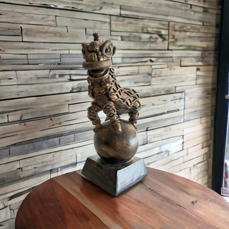 Eine Holzstatue eines Löwen auf einer Holzkugel.